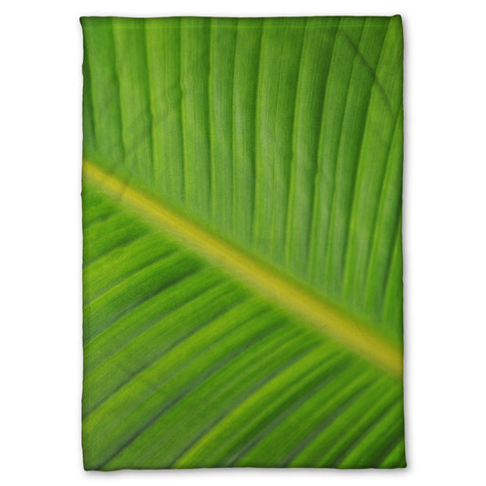 A fleece throw blanket designed with a closeup photo of a leaf of a bird of paradise palm, showing all the detail of the midrib and veins of the leaf.