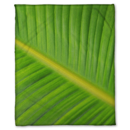 A fleece throw blanket designed with a closeup photo of a leaf of a bird of paradise palm, showing all the detail of the midrib and veins of the leaf.