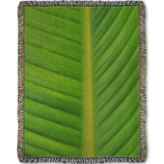 A woven throw blanket designed with a closeup photo of a bird of paradise leaf, showing all the detail of the midrib and veins of the leaf.