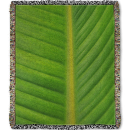 A woven throw blanket designed with a closeup photo of a bird of paradise leaf, showing all the detail of the midrib and veins of the leaf.