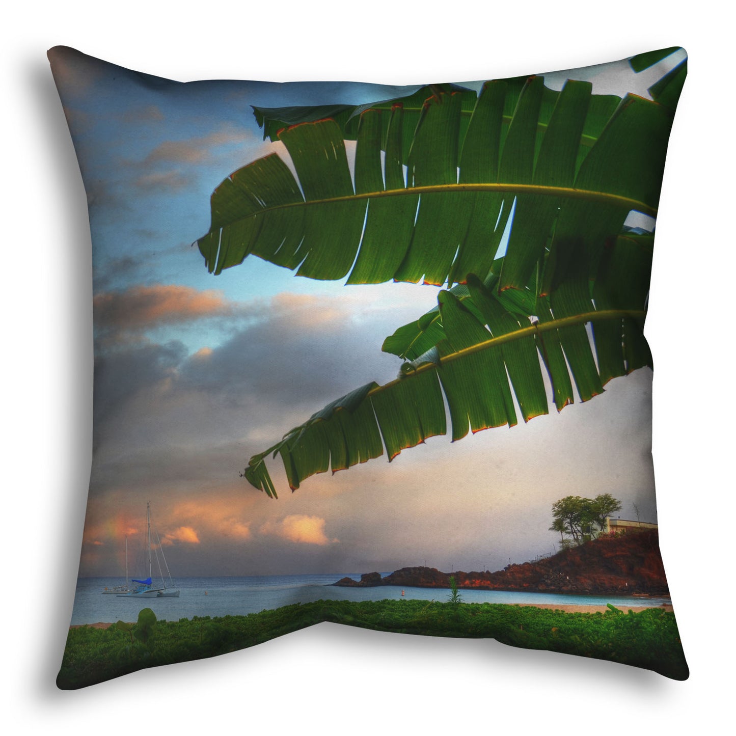 A throw pillow designed with a photo of Ka'anapali beach in Hawai'i. Boats can be seen sailing on the ocean, and bright green plants grow in the foreground alongside a palm.