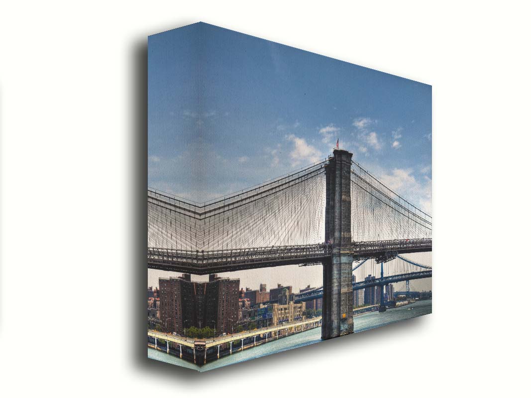 A photo of a side view of the Brooklyn Bridge against a blue sky. Printed on canvas.