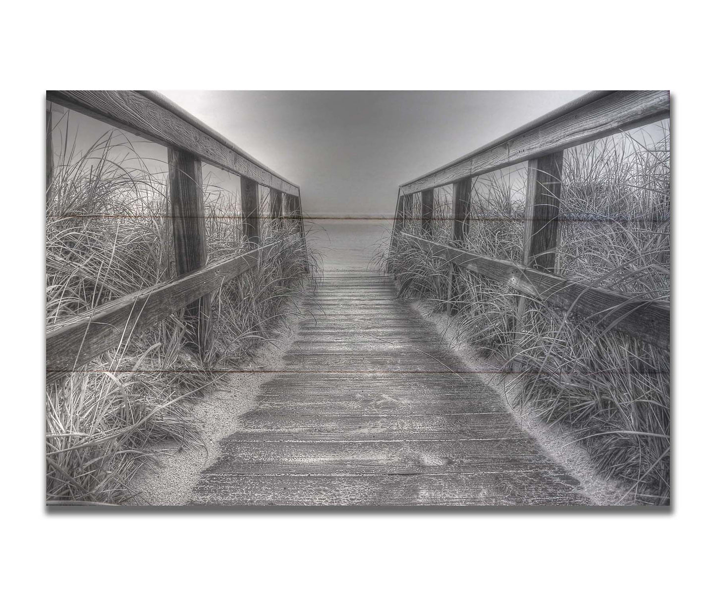 A grayscale photo looking down a wooden railed path on the beach at Cape Cod. Printed on a box board.