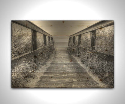 A grayscale photo looking down a wooden railed path on the beach at Cape Cod. Printed on a wood pallet.