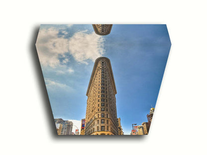 A photo of the Flatiron Building in New York City, New York. Its iconic triangular shape is captures against a bright blue sky. Printed on canvas.