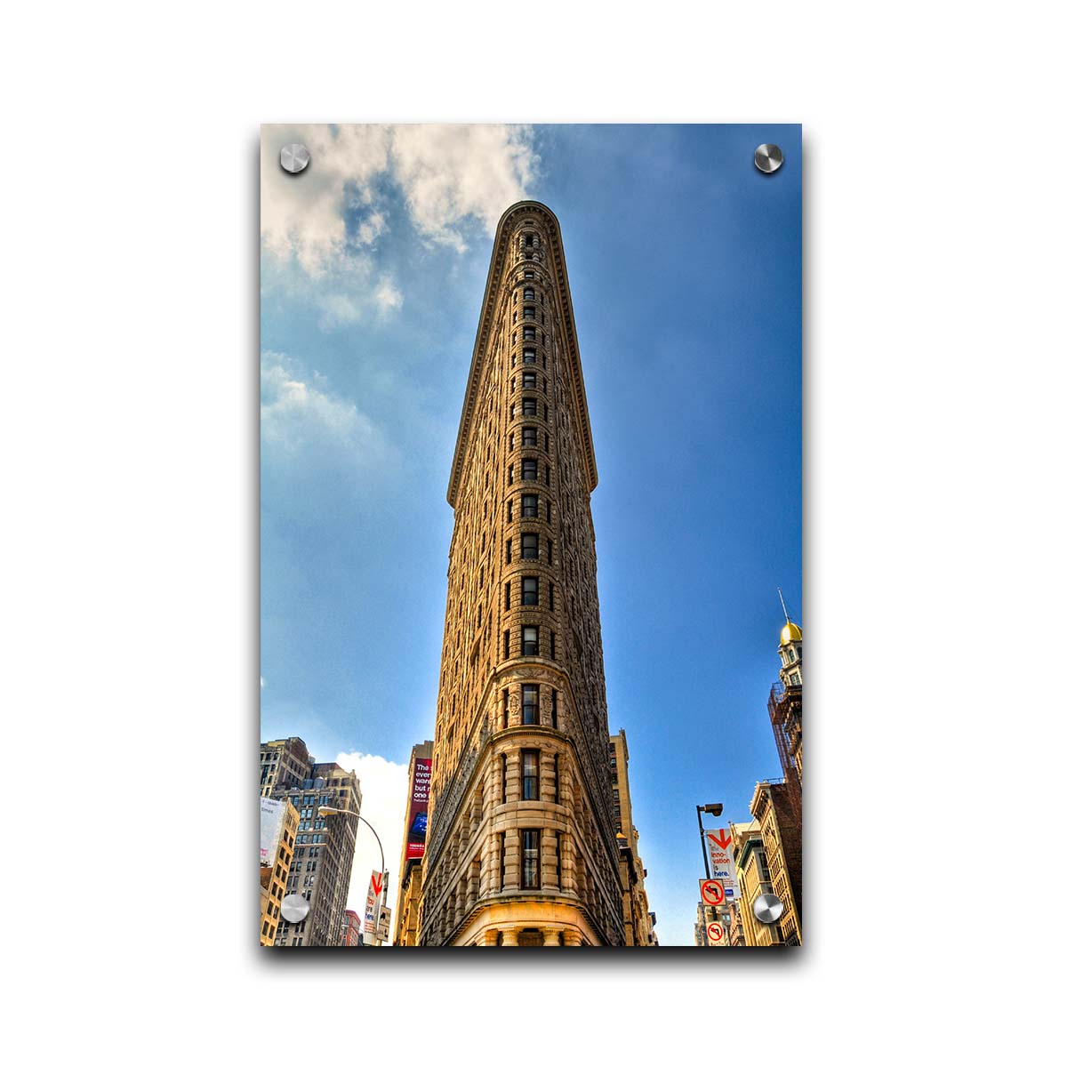 A photo of the Flatiron Building in New York City, New York. Its iconic triangular shape is captures against a bright blue sky. Printed on acrylic.