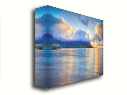 A photo of the ocean at Hanalei Bay at sunset. Clouds rest atop the mountains and reflect the golden light. Printed on canvas.