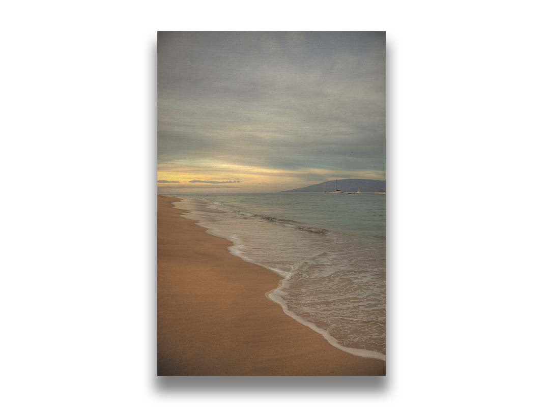 A photo of a cloudy sunrise on the Kaʻanapali shore, looking out to sea. Sailboats can be seen out on the water. Printed on canvas.