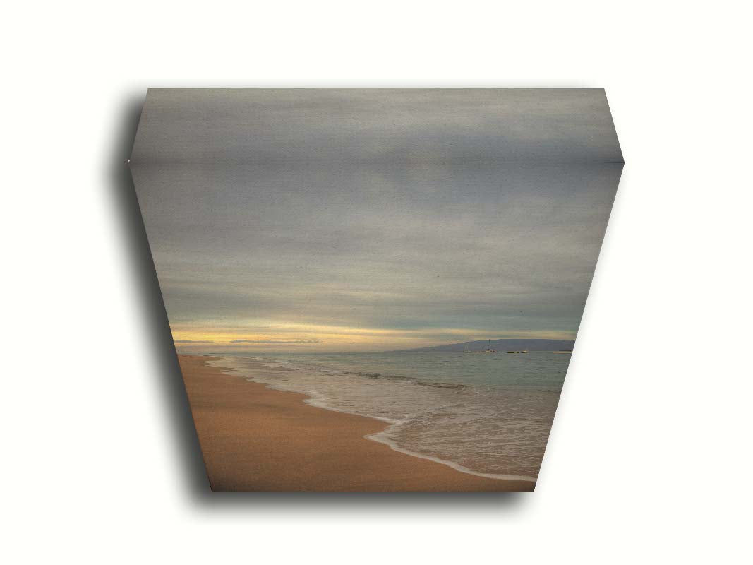 A photo of a cloudy sunrise on the Kaʻanapali shore, looking out to sea. Sailboats can be seen out on the water. Printed on canvas.