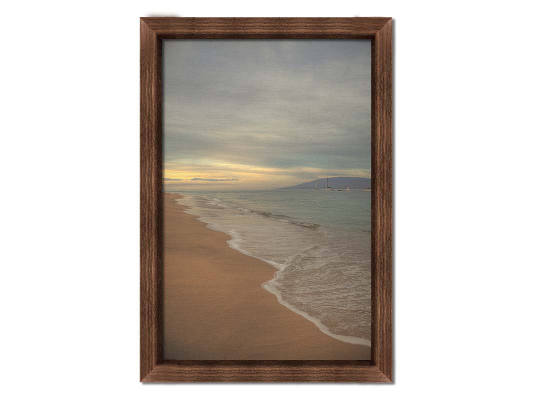 A photo of a cloudy sunrise on the Kaʻanapali shore, looking out to sea. Sailboats can be seen out on the water. Printed on canvas and framed.