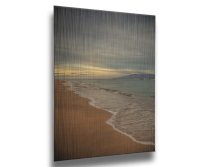 A photo of a cloudy sunrise on the Kaʻanapali shore, looking out to sea. Sailboats can be seen out on the water. Printed on metal.