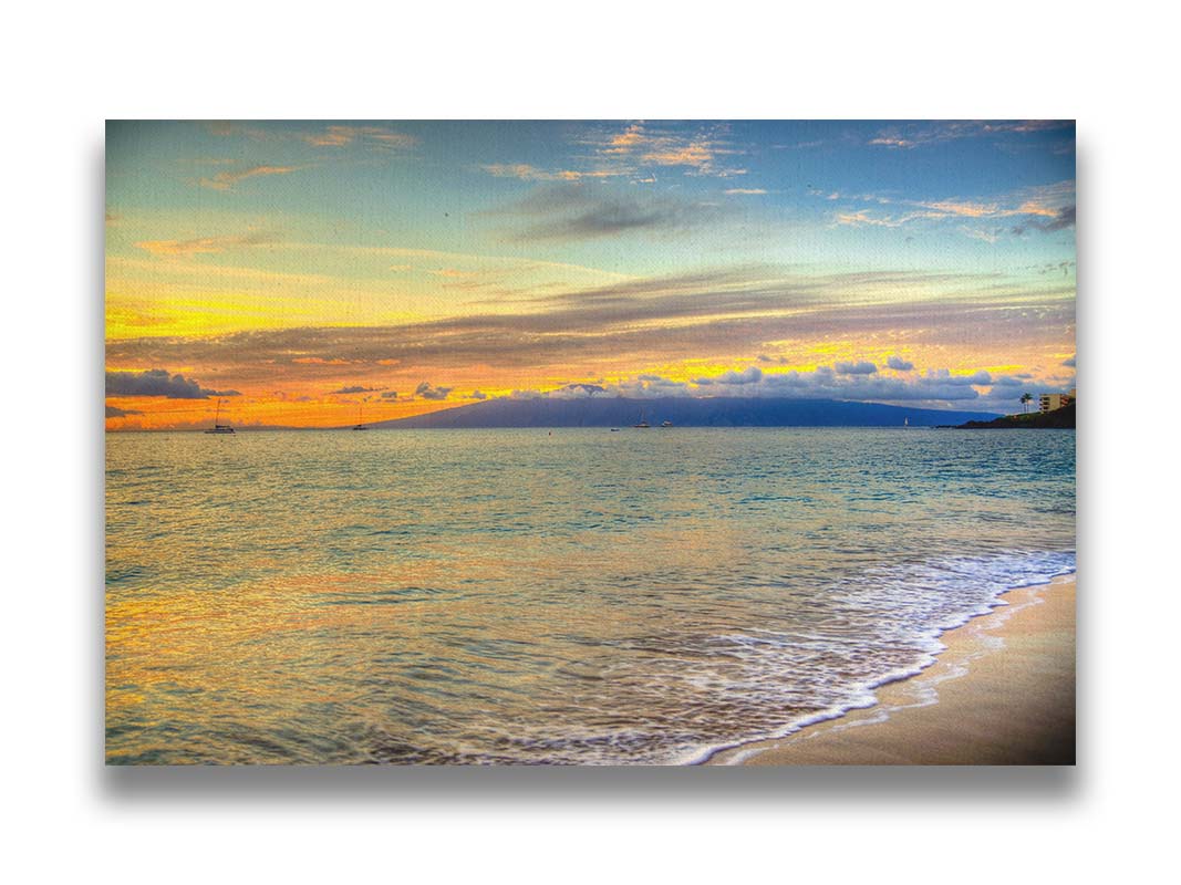 A photo of the sunset on the beach at Kaʻanapali, looking out to sea. Sailboats can be seen on the water, and mountains stand tall among clouds in the background. Printed on canvas.