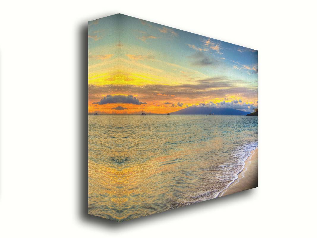 A photo of the sunset on the beach at Kaʻanapali, looking out to sea. Sailboats can be seen on the water, and mountains stand tall among clouds in the background. Printed on canvas.