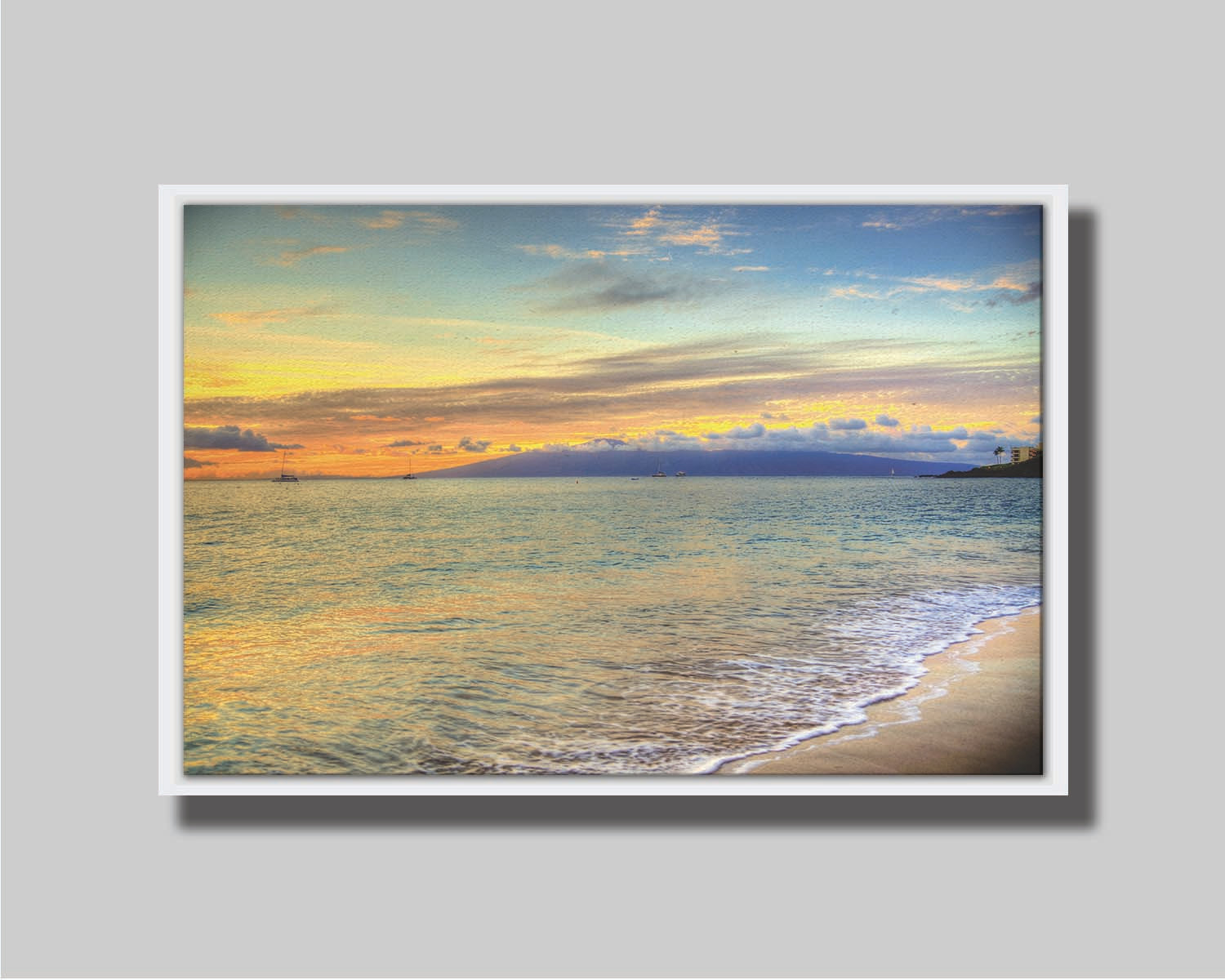 A photo of the sunset on the beach at Kaʻanapali, looking out to sea. Sailboats can be seen on the water, and mountains stand tall among clouds in the background. Printed on canvas in a float frame.