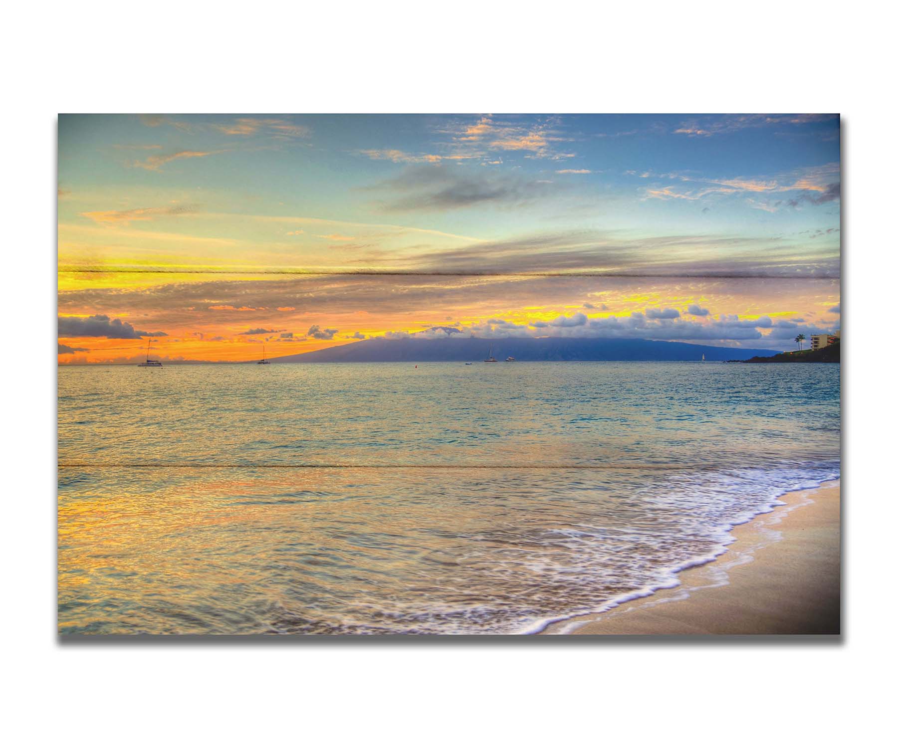 A photo of the sunset on the beach at Kaʻanapali, looking out to sea. Sailboats can be seen on the water, and mountains stand tall among clouds in the background. Printed on a box board.