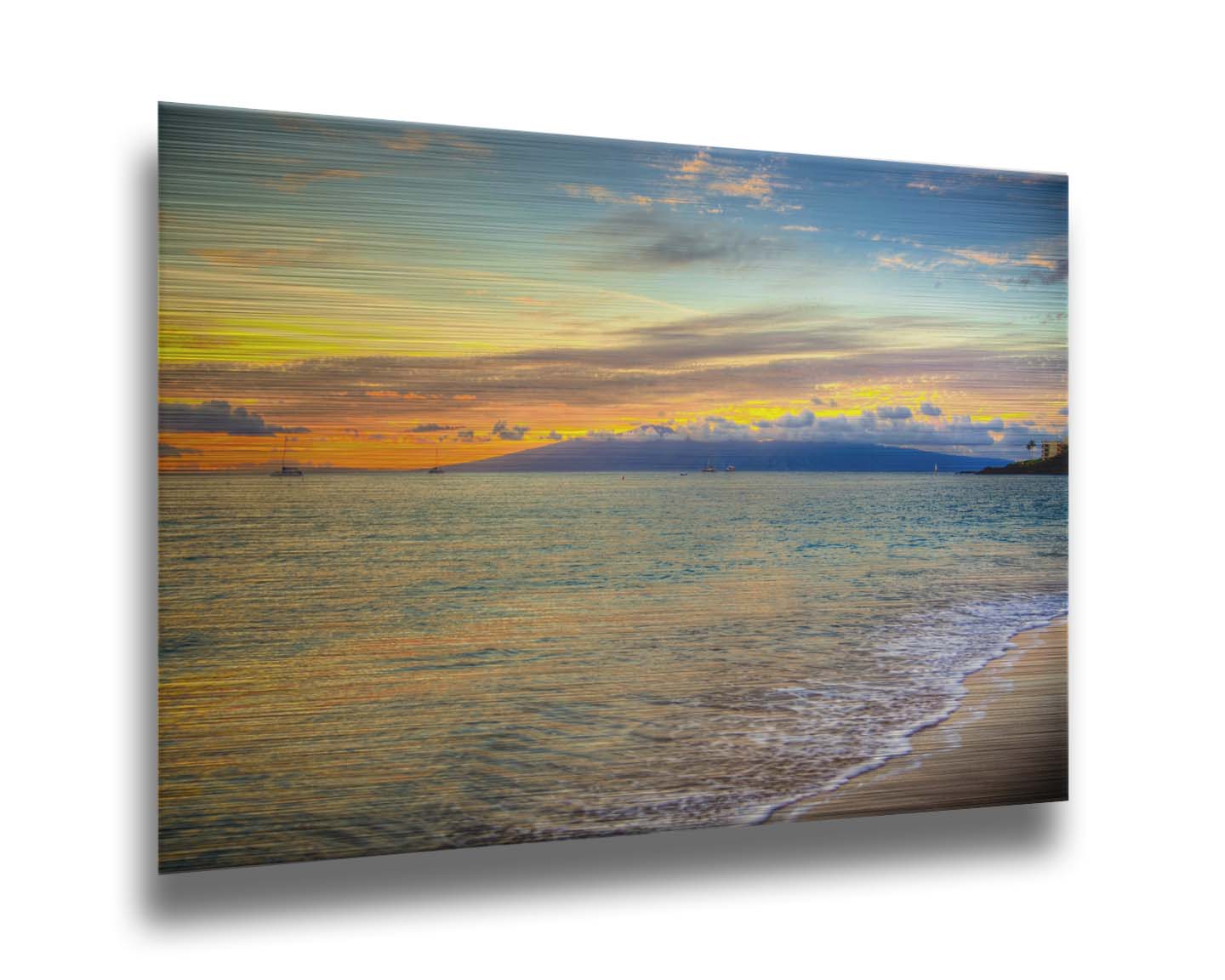 A photo of the sunset on the beach at Kaʻanapali, looking out to sea. Sailboats can be seen on the water, and mountains stand tall among clouds in the background. Printed on metal.