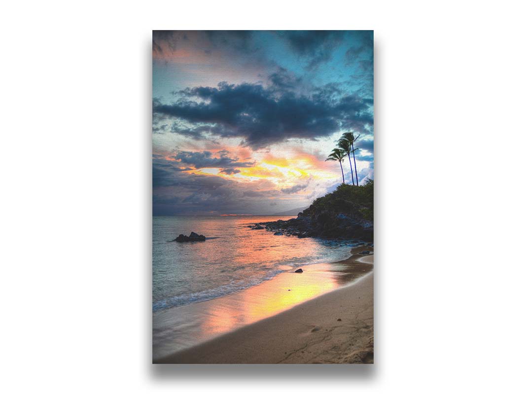 A photo of the sunset at Honokahua, Maui peeking through the clouds and reflecting pink and orange on the water. Palms are silhouetted against the sky. Printed on canvas.