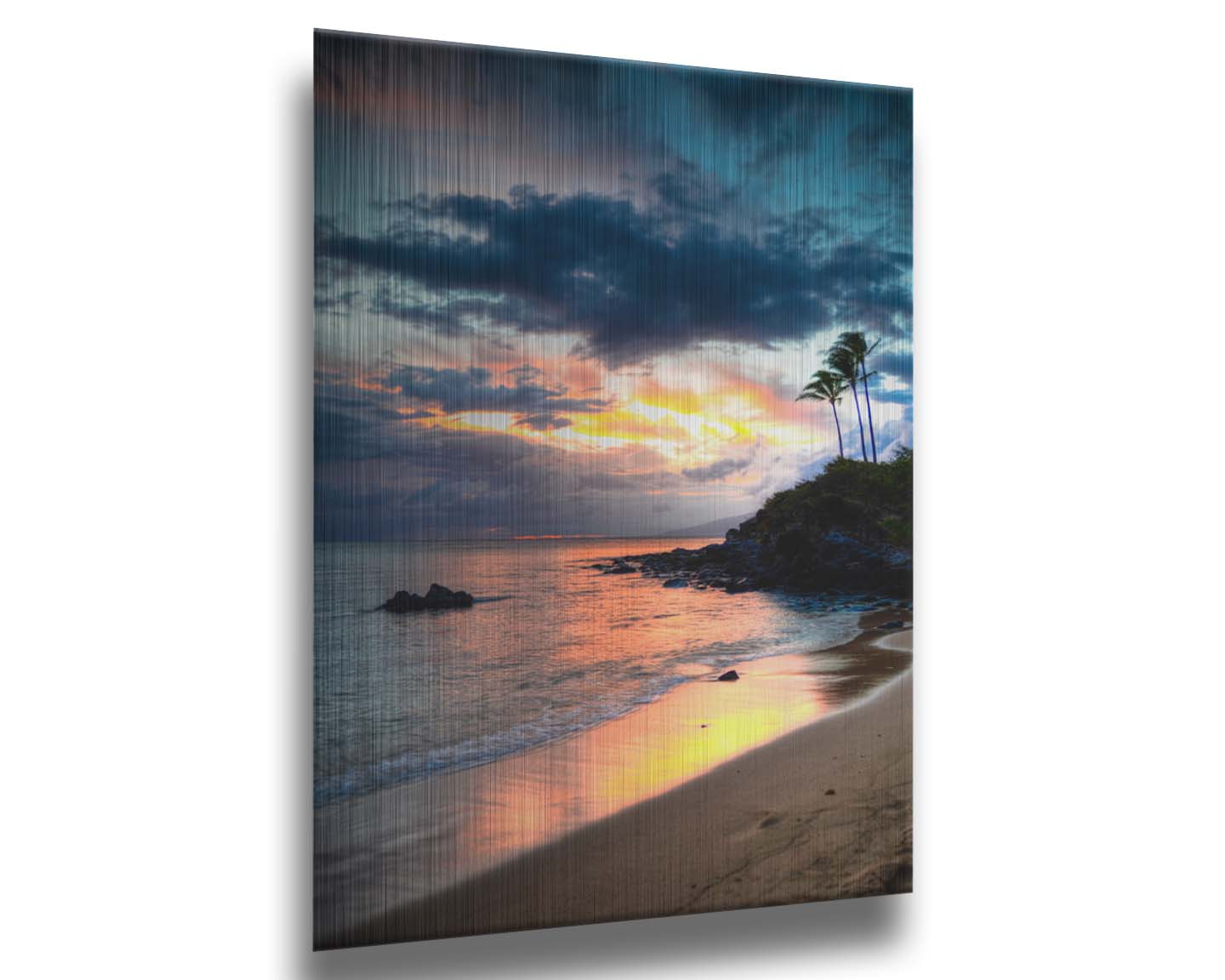 A photo of the sunset at Honokahua, Maui peeking through the clouds and reflecting pink and orange on the water. Palms are silhouetted against the sky. Printed on metal.