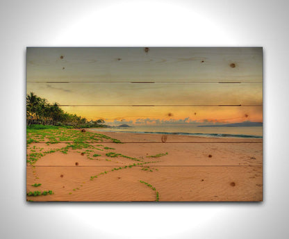 A photo of Keawakapu Beach at sunrise, with palms and mountains in the distance. Printed on a wood pallet.