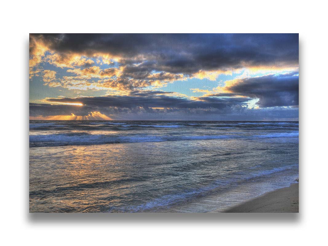 A photo looking out to sea off the coast of Kauaʻi at sunrise. The sunlight reflects off the sea and clouds in a beautiful parallel. Printed on canvas.