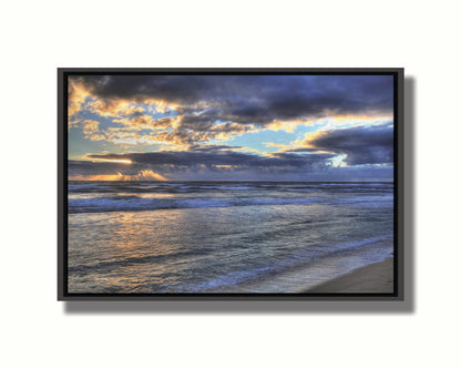 A photo looking out to sea off the coast of Kauaʻi at sunrise. The sunlight reflects off the sea and clouds in a beautiful parallel. Printed on canvas in a float frame.