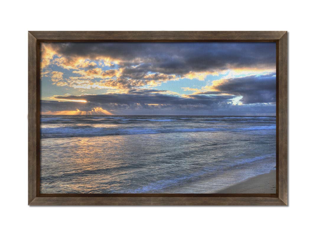 A photo looking out to sea off the coast of Kauaʻi at sunrise. The sunlight reflects off the sea and clouds in a beautiful parallel. Printed on canvas and framed.