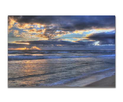 A photo looking out to sea off the coast of Kauaʻi at sunrise. The sunlight reflects off the sea and clouds in a beautiful parallel. Printed on a box board.