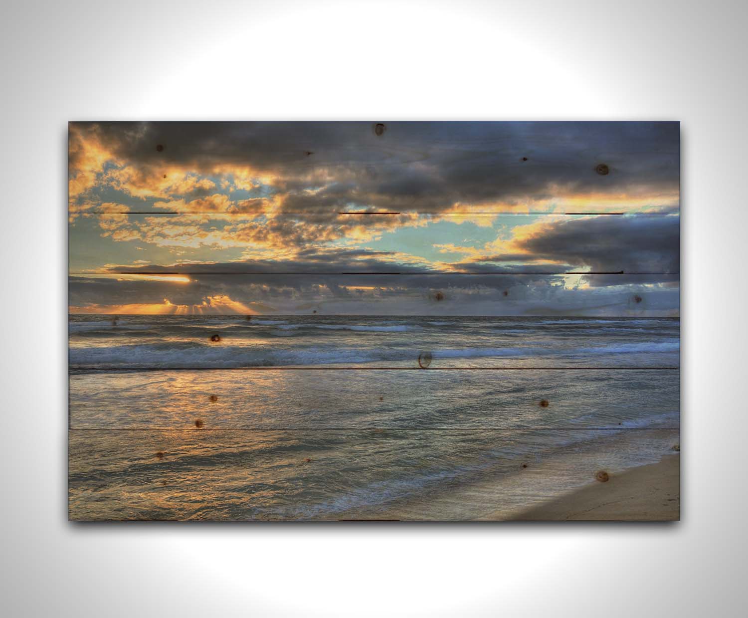 A photo looking out to sea off the coast of Kauaʻi at sunrise. The sunlight reflects off the sea and clouds in a beautiful parallel. Printed on a wood pallet.