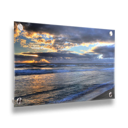 A photo looking out to sea off the coast of Kauaʻi at sunrise. The sunlight reflects off the sea and clouds in a beautiful parallel. Printed on acrylic.