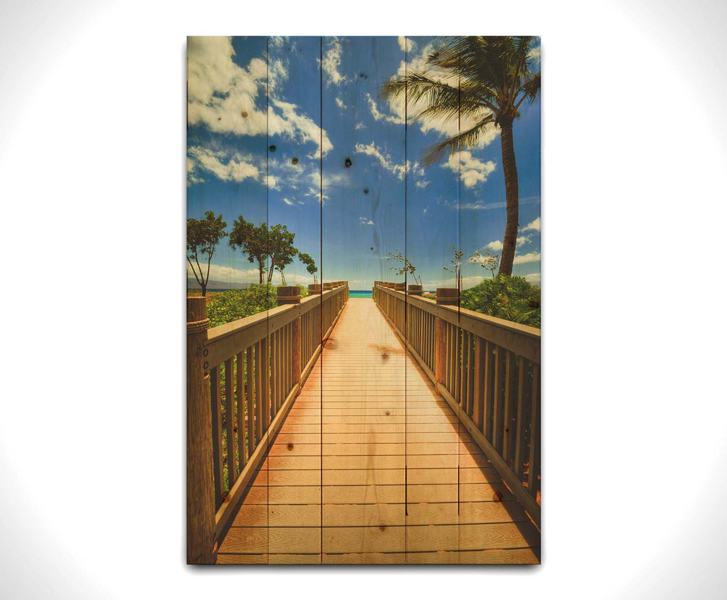 A photo of a boardwalk in Maui, Hawaiʻi, looking down the wood path to the sea. It is flanked by shrubbery, palms, and other tropical trees. Printed on a wood pallet.