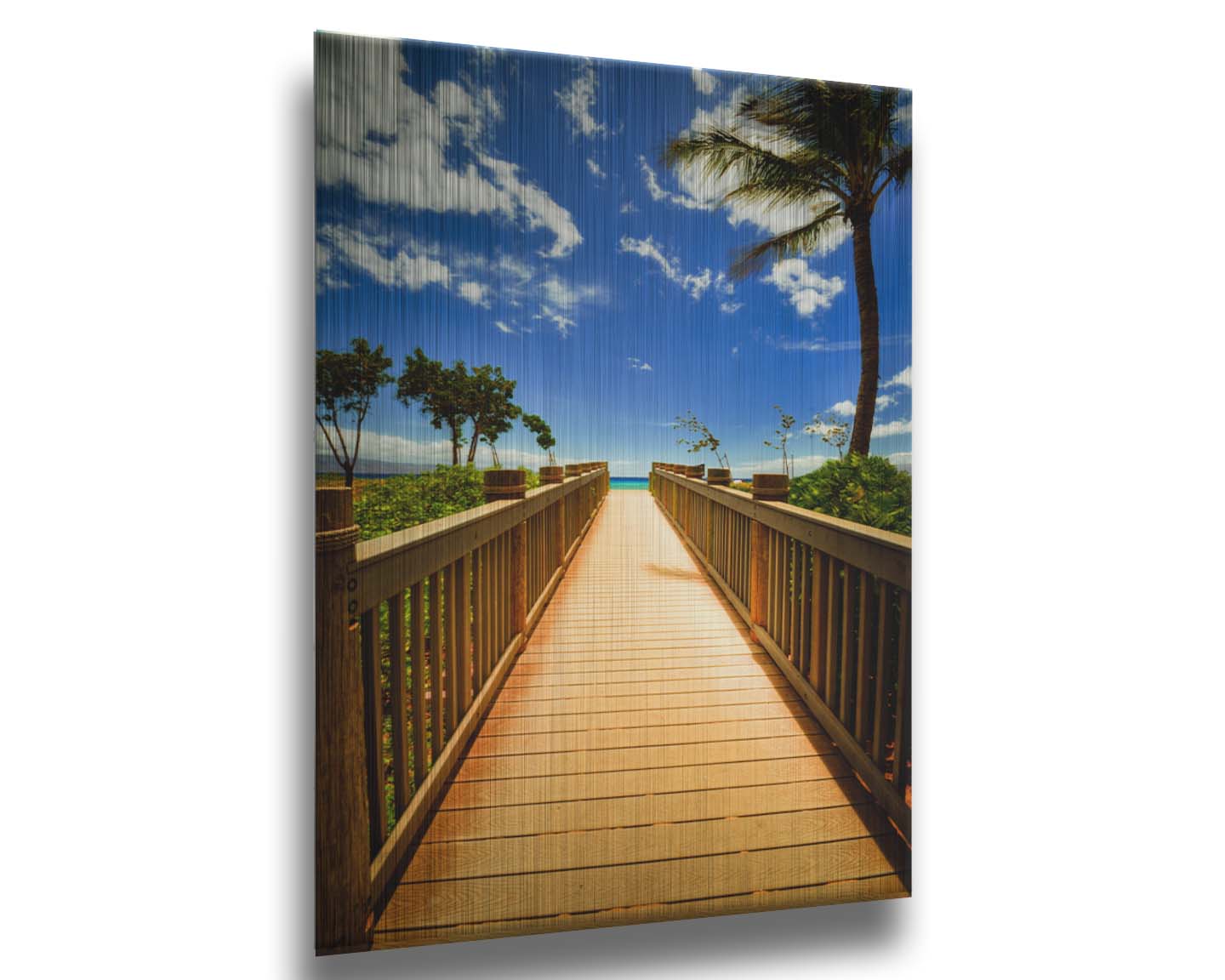 A photo of a boardwalk in Maui, Hawaiʻi, looking down the wood path to the sea. It is flanked by shrubbery, palms, and other tropical trees. Printed on metal.