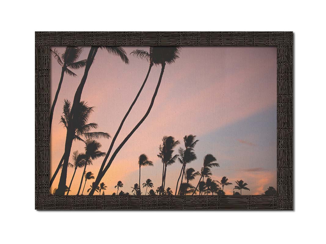 A photo of many palm trees silhouetted against a colorful sunrise reflecting pinks and yellows off the clouds. Printed on canvas and framed.