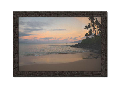 A photo looking out to sea at Maui during sunrise. A surfer can be seen on the water in the distance. Printed on canvas and framed.