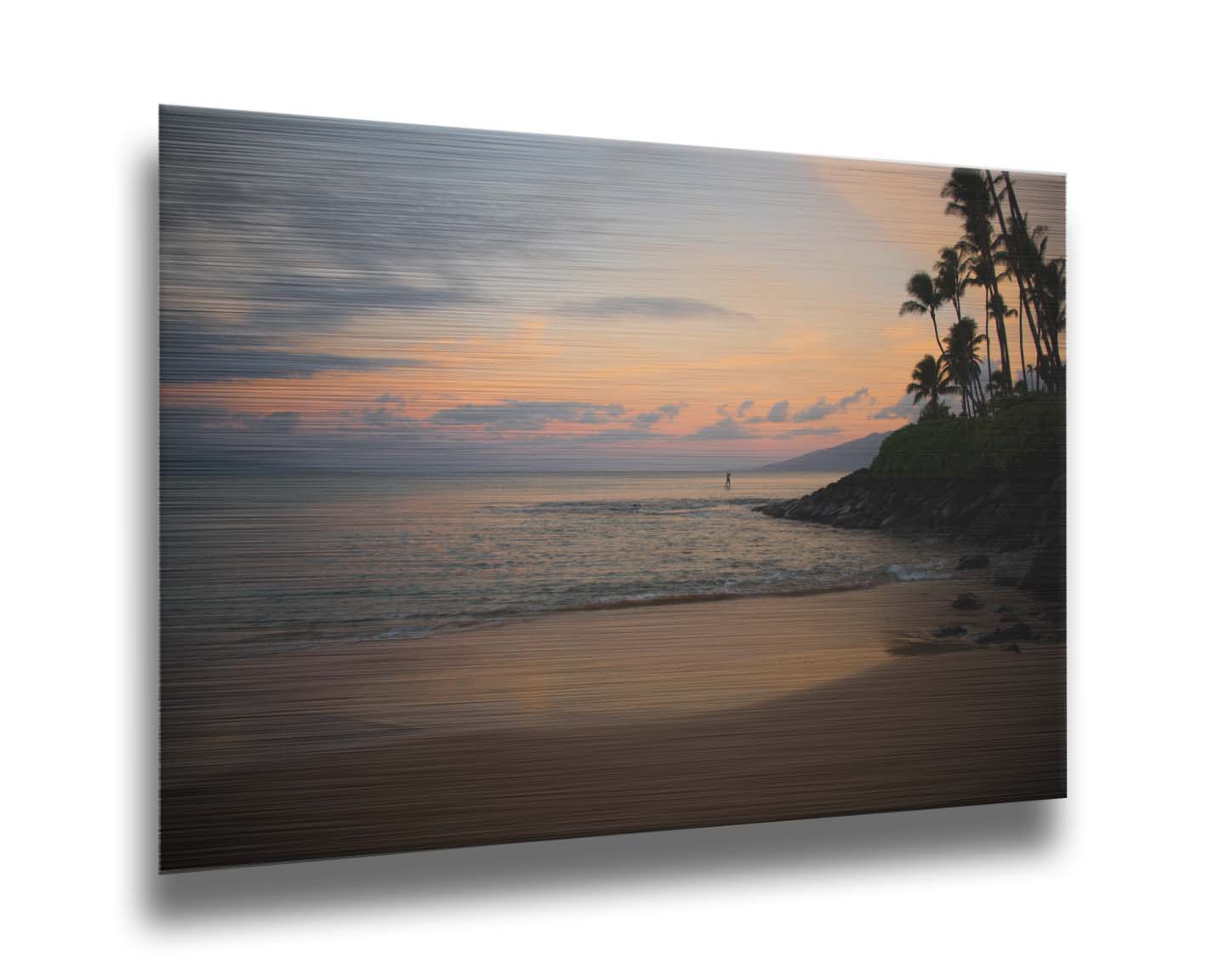 A photo looking out to sea at Maui during sunrise. A surfer can be seen on the water in the distance. Printed on metal.