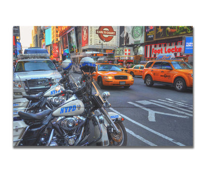 A photo of a street in New York City, featuring several bright orange taxis and New York Police Department vehicles. Printed on a box board.