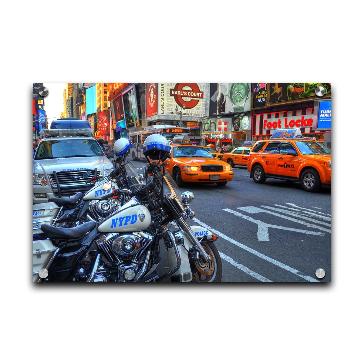 A photo of a street in New York City, featuring several bright orange taxis and New York Police Department vehicles. Printed on acrylic.