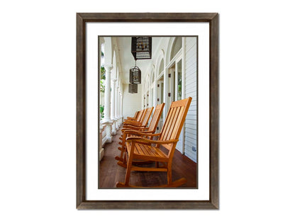 A photo looking down a row of rocking chairs on a porch in O'ahu, Hawaiʻi. Printed on paper, matted, and framed.