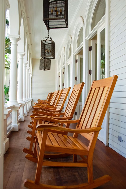 A photo looking down a row of rocking chairs on a porch in O'ahu, Hawaiʻi. 