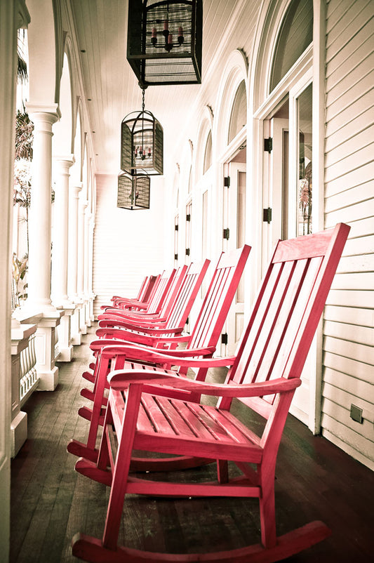 A photo looking down a row of rocking chairs on a porch in O'ahu, Hawaiʻi. 