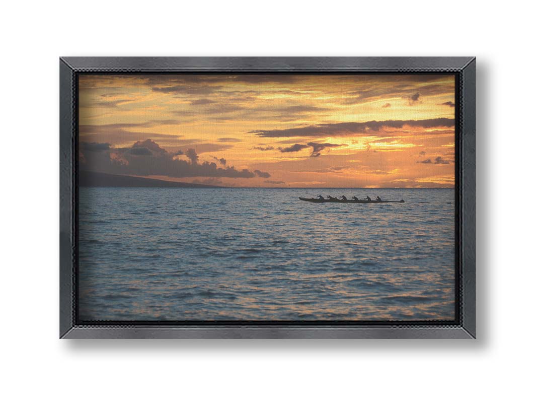 A photo of an outrigger canoe silhouetted on the sea by an orange sunset off the coat of Hawaiʻi. Printed on canvas and framed.