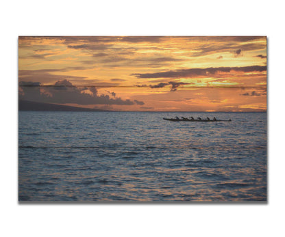 A photo of an outrigger canoe silhouetted on the sea by an orange sunset off the coat of Hawaiʻi. Printed on a box board.