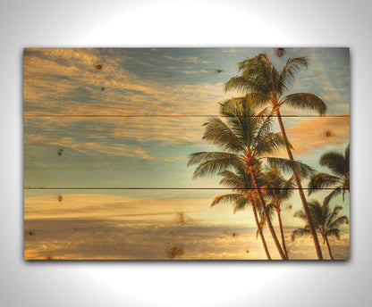 Photograph of palm trees set against the morning sky by the orange hues of the sunrise. Printed on a wood pallet.