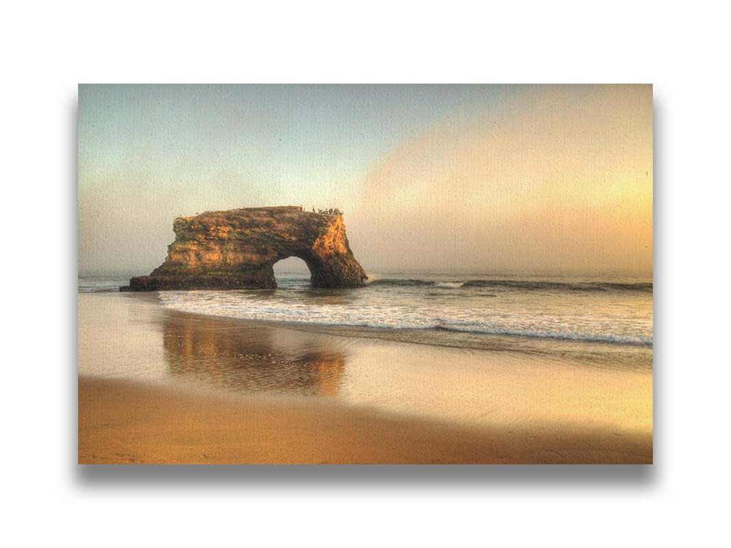 A photo of a "natural bridge" rock formation in Santa Cruz, California. A group of pelicans sit on top of the structure above the sea. Printed on canvas.