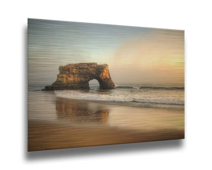 A photo of a "natural bridge" rock formation in Santa Cruz, California. A group of pelicans sit on top of the structure above the sea. Printed on metal.