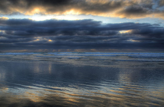 A photo of the sea at La Jolla as viewed near the Ellen Browning Scripps Memorial Research Pier. Rays of light can be seen shining down onto the sea from the cloudy sky. 