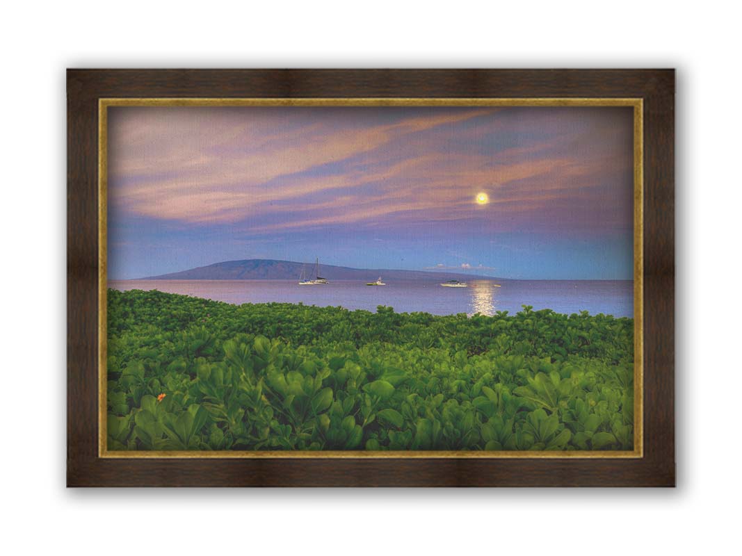 A photo overlooking the sea off the coast of Hawaiʻi as the moon sets. The foreground is filled with greenery, and ships can be seen sailing on the waters with mountains in the distance. Printed on canvas and framed.