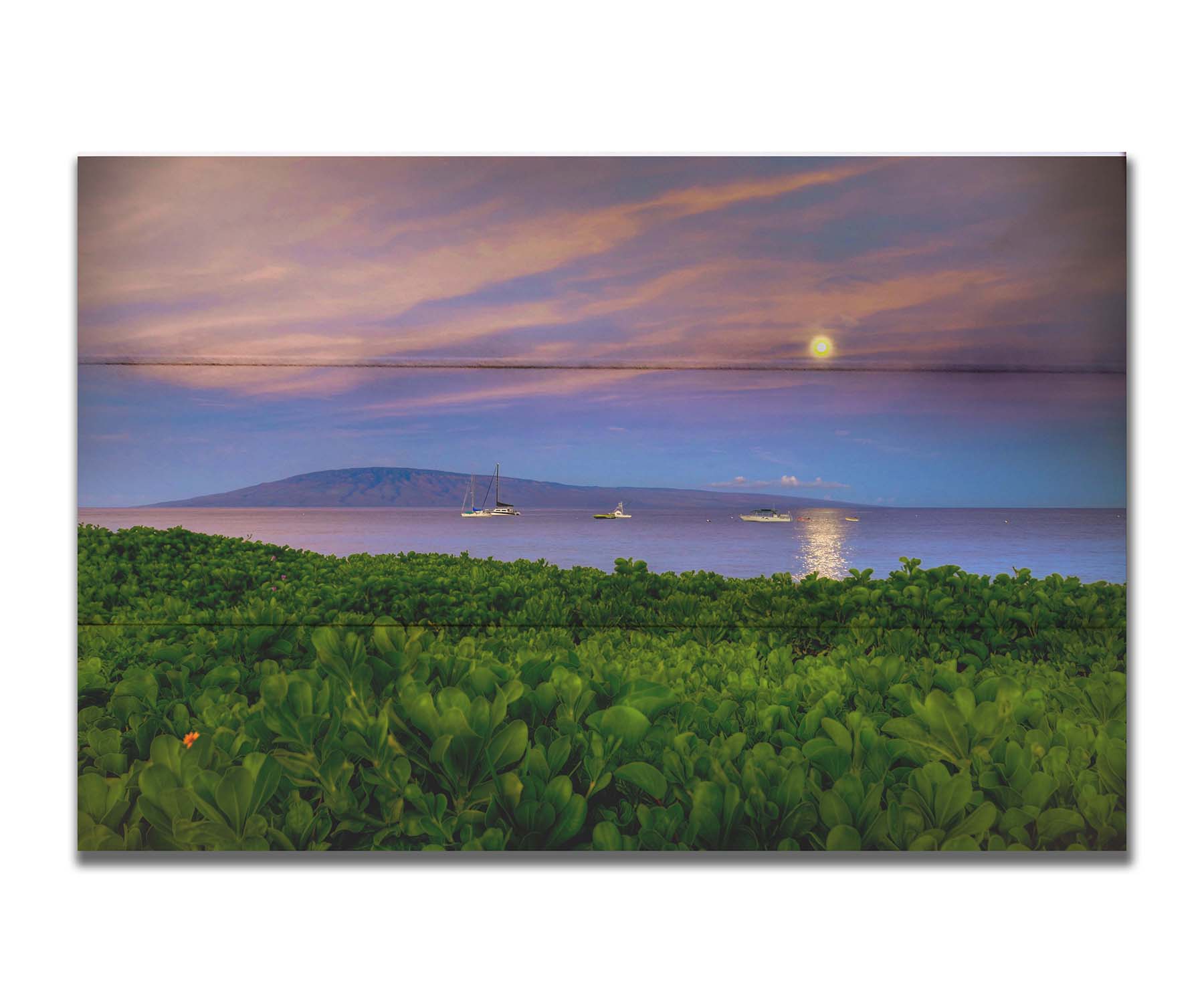 A photo overlooking the sea off the coast of Hawaiʻi as the moon sets. The foreground is filled with greenery, and ships can be seen sailing on the waters with mountains in the distance. Printed on a box board.