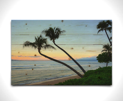 A photo of palm trees silhouetted against the sunrise sky of Hawaiʻi. Printed on a wood pallet.