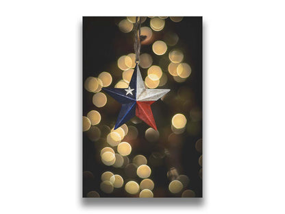 A photo of a christmas ornament of a star painted like the Texas state flag, with yellow bokeh in the background. Printed on canvas.