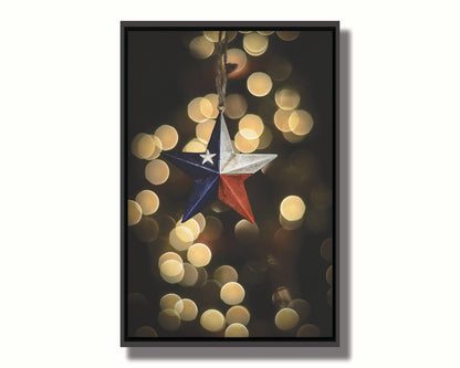 A photo of a christmas ornament of a star painted like the Texas state flag, with yellow bokeh in the background. Printed on canvas in a float frame.